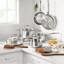 Stainless steel cookware set on kitchen counter with lids and wooden utensils