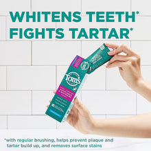 Fluoride-free mint antiplaque and whitening toothpaste box held near bathroom tiles.
