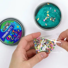 Thinking putty tin and a clear packet filled with colorful mix-ins held in hands