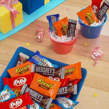 Assorted chocolate candy bars in cups with a few wrappers on a wooden table