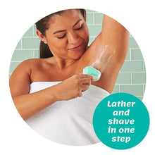 Women shaving with teal-handled razor over lathered skin, towel nearby.
