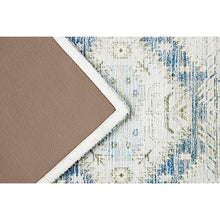 Rectangular geometric rug corner with cream edge and blue distressed motif stitching