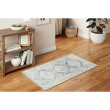 Geometric rectangular area rug with cream base and blue distressed pattern