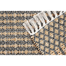 Woven rug close-up with black-and-white check pattern, beige threads, and fringed texture