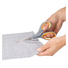 Titanium-bonded scissors with orange handles cutting a gray fabric strip