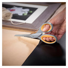 Titanium-bonded scissors with orange handles cutting paper on a mat