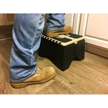 Plastic step stool in black with beige platform rim and striped anti-slip tread