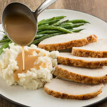 Seasoned sliced chicken breast with mashed potatoes, green beans, and gravy