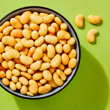 Bowl of peach yogurt covered cashews with loose cashews around it