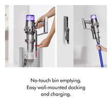 Dyson V11 cordless vacuum at wall dock, hands inserting canister
