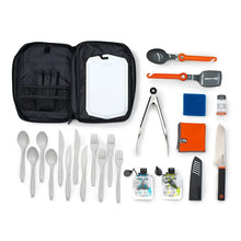 Camp kitchen set accessories laid out: spoons, forks, orange-handled tools, cloth, bottles