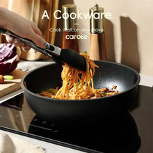 Black nonstick skillet cooking spaghetti, with wooden-handled utensil resting on the rim