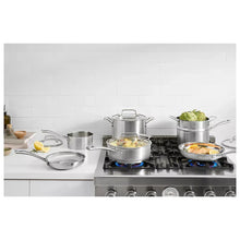 Stainless steel pots and pans with lids on gas stove, cooktop view