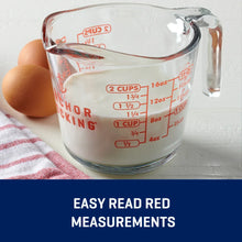 Clear glass measuring cup with handle, filled with milk and red 2 cup measurement markings