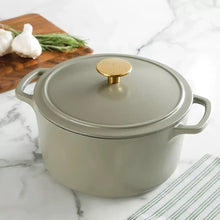 Sage green enamel cast iron Dutch oven with lid and gold knob, curved side handles