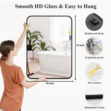 Bathroom wall mirror with black frame and rounded corners, shown being mounted.