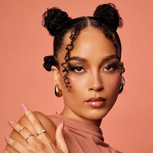 Model with styled curls, hands near face, wearing makeup