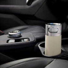 Light-colored insulated travel mug with AutoSeal lid in a car cupholder