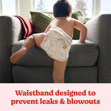 Baby in white-and-gold printed diaper sitting on couch