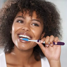 Electric toothbrush with blue bristles, held in hand while brushing