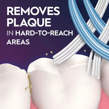 Toothbrush bristles cleaning a white tooth with small debris near the gumline