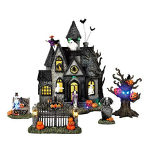 Haunted Halloween village house ornament with windows, ghosts, pumpkins, and tree