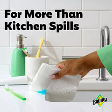 White paper towel held over a kitchen sink area to clean spills