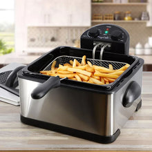Stainless steel deep fryer with open lid, basket of fries, and black side handles