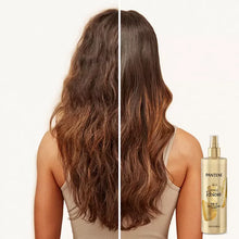 Hair multitasking spray bottle next to long wavy brown hair