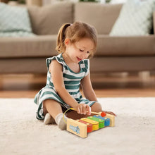 Child playing wooden xylophone band toy with colorful bars and mallets