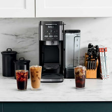 Black drip coffee maker with glass carafe, tall reservoir, and coffee cups