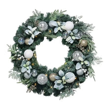 Green faux floral wreath with white faux flowers, silver ornaments, and LED lights