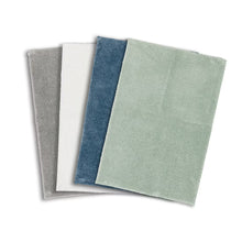 Set of plush bath rugs: gray, white, blue, and light green, rectangular.