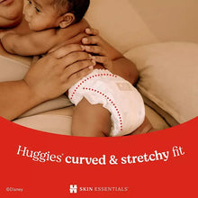 Baby wearing white diapers with curved & stretchy fit callout on packaging