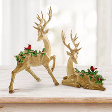 Set of 2 golden deer figurines on bases, each holding green wreath with red berries
