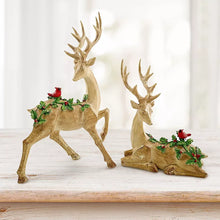 Two golden deer figurines with antlers, each with a greenery cluster and red berries