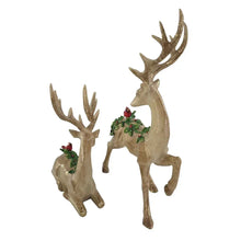Golden deer figurines with antlers, showing greenery and red berry detail on their backs
