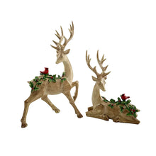 Pair of golden deer figurines with antlers, each topped with greenery and red berries