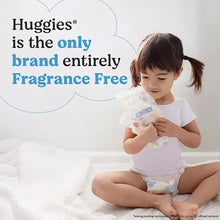 Baby wearing a white printed diaper while holding it, with fragrance-free claim text