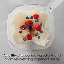 Blender jar with creamy mixture and mixed berries inside the clear container