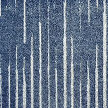Blue area rug close-up with vertical distressed stripes and short textured pile.