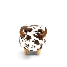 Cow ottoman stool with brown patches, horned ears, and wooden legs