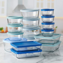 Stacked clear food storage containers with blue and light teal lids, snap-on bases