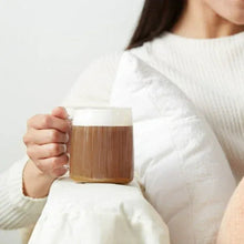 Dark roast coffee in a clear mug, held by a person