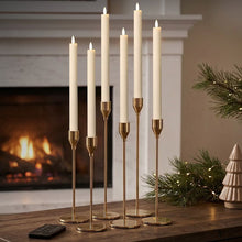 Wax-style LED taper candles in gold brass holders with remote on tabletop