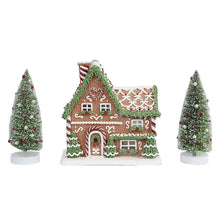 Prelit gingerbread house decoration with two snowy pine trees and decorated front arch