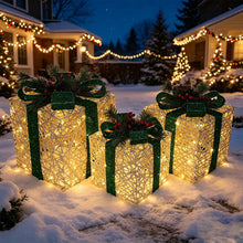 Set of three lighted gold gift boxes with green ribbons, pine, and red berries