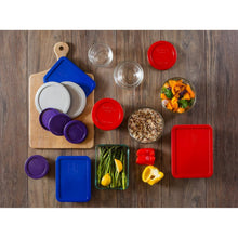 Assorted glass storage containers with colorful snap lids arranged on wooden board
