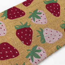 Coir outdoor mat close-up with strawberry pattern, tan with red and pale pink fruits.