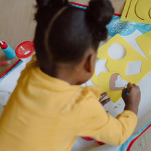 Child drawing on a doodle mat with colorful shapes and star-like play areas